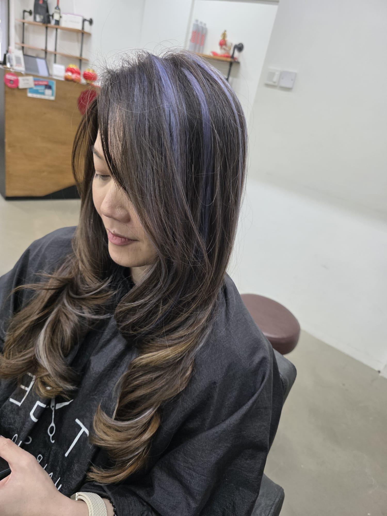 Brown hair with violet peekaboo highlights and curled ends styled at Stage Hair Studio